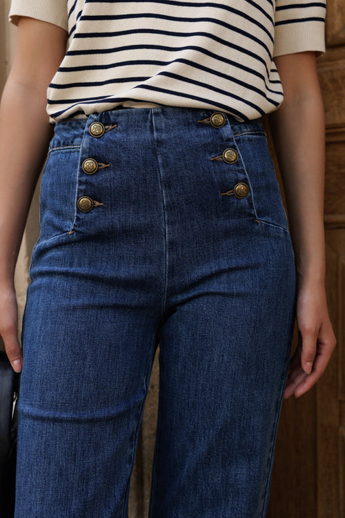 Person wearing blue jeans with gold buttons and a striped shirt. Jeans_Victor_Blue_denim_Maison_Torrini_Paris